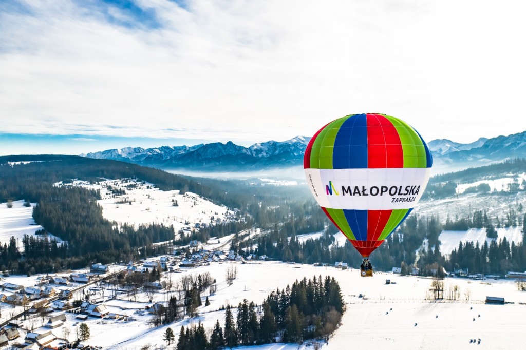 Kolorowy balon z napisem Małopolska na zimowym tle gór i lasów